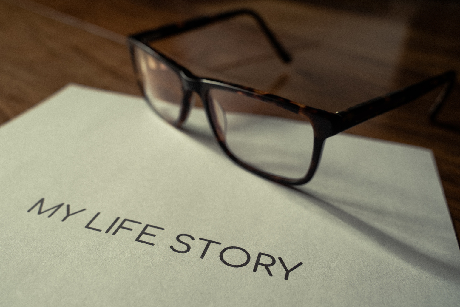 My life story wording title printed on paper highlighted on a wooden walnut floor